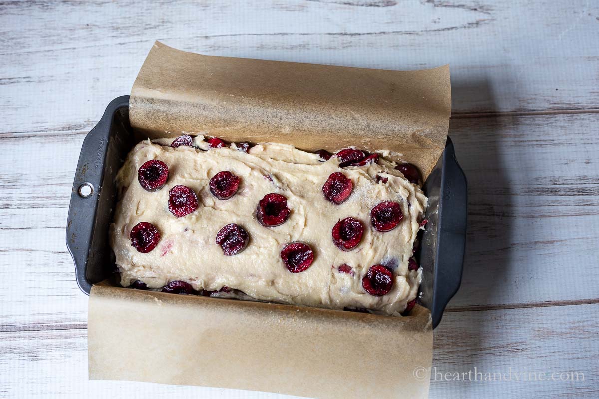 Cherry loaf cake with halved cherries on top ready to go into the oven.