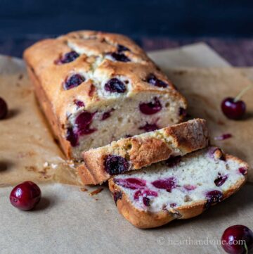 A cherry loaf cake on parchment with a few slices.