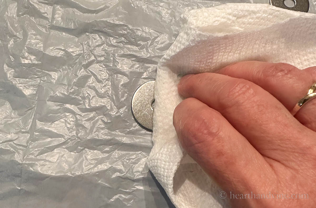 A hand wiping a washer clean with a paper towel.