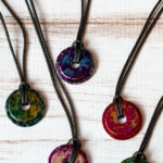 Five washer necklaces decorated with alcohol inks.