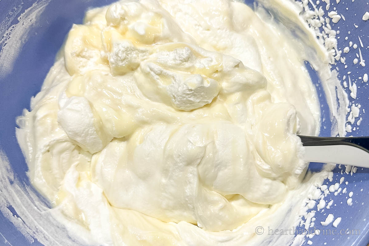 Folding sweetened condensed milk into whipped cream.