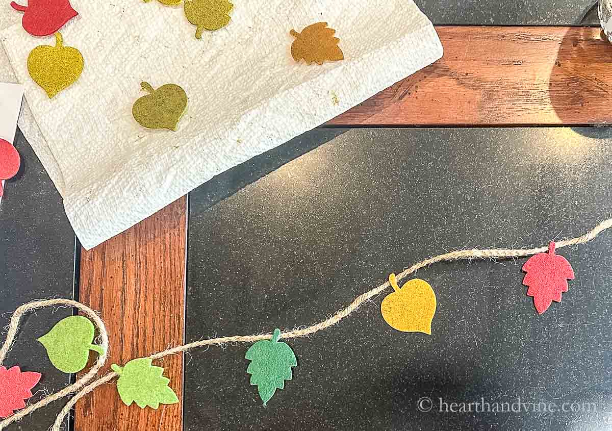 Gluing leaves to twine on a table.