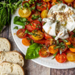 Burrata caprese salad with slices of baguette on the side.