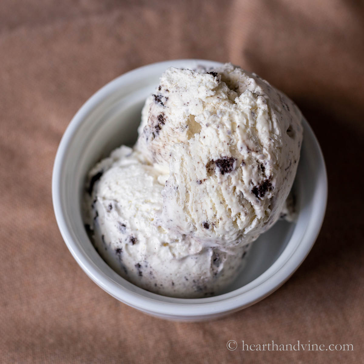 White bowl with two scoops of Oreo ice cream.