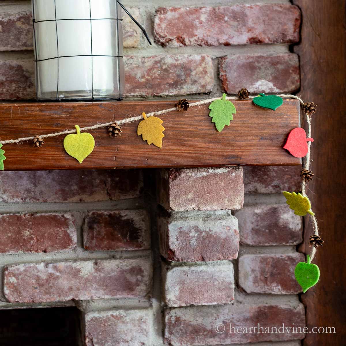 Felt fall leaf and pinecone garland on the corner of a mantel.