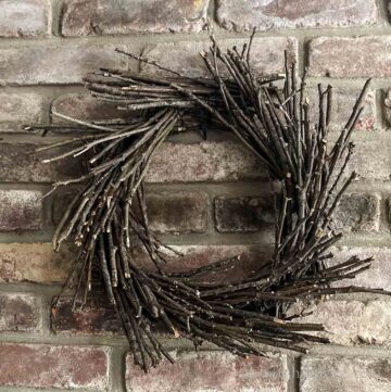 Handmade twig wreath hung on a brick wall.