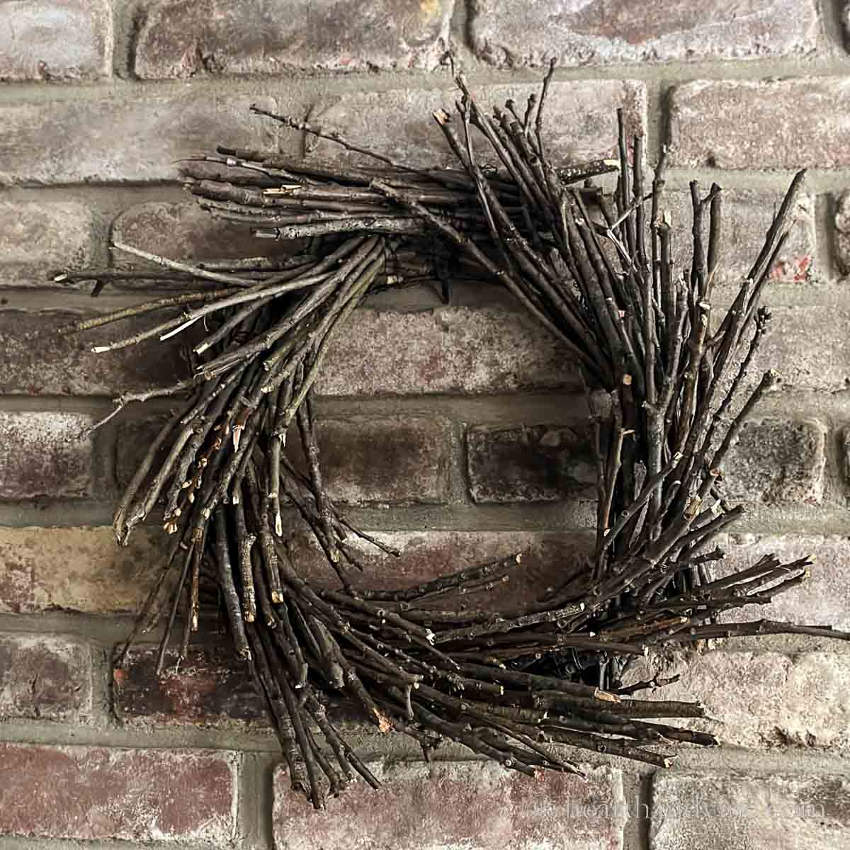 Handmade twig wreath hung on a brick wall.