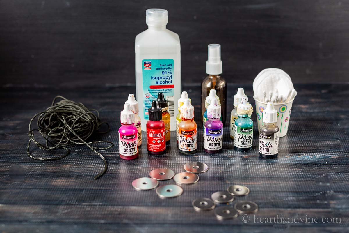 Supplies for alcohol ink washer necklaces including cording, isopropyl alcohol, alcohol ink bottles, washers, and cotton swabs/pads.
