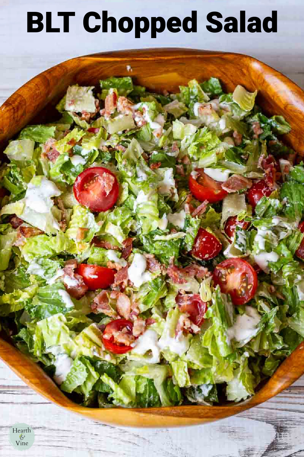 Large wooden salad bowl with a chopped bacon lettuce and tomato salad dressed with cream blue cheese dressing.