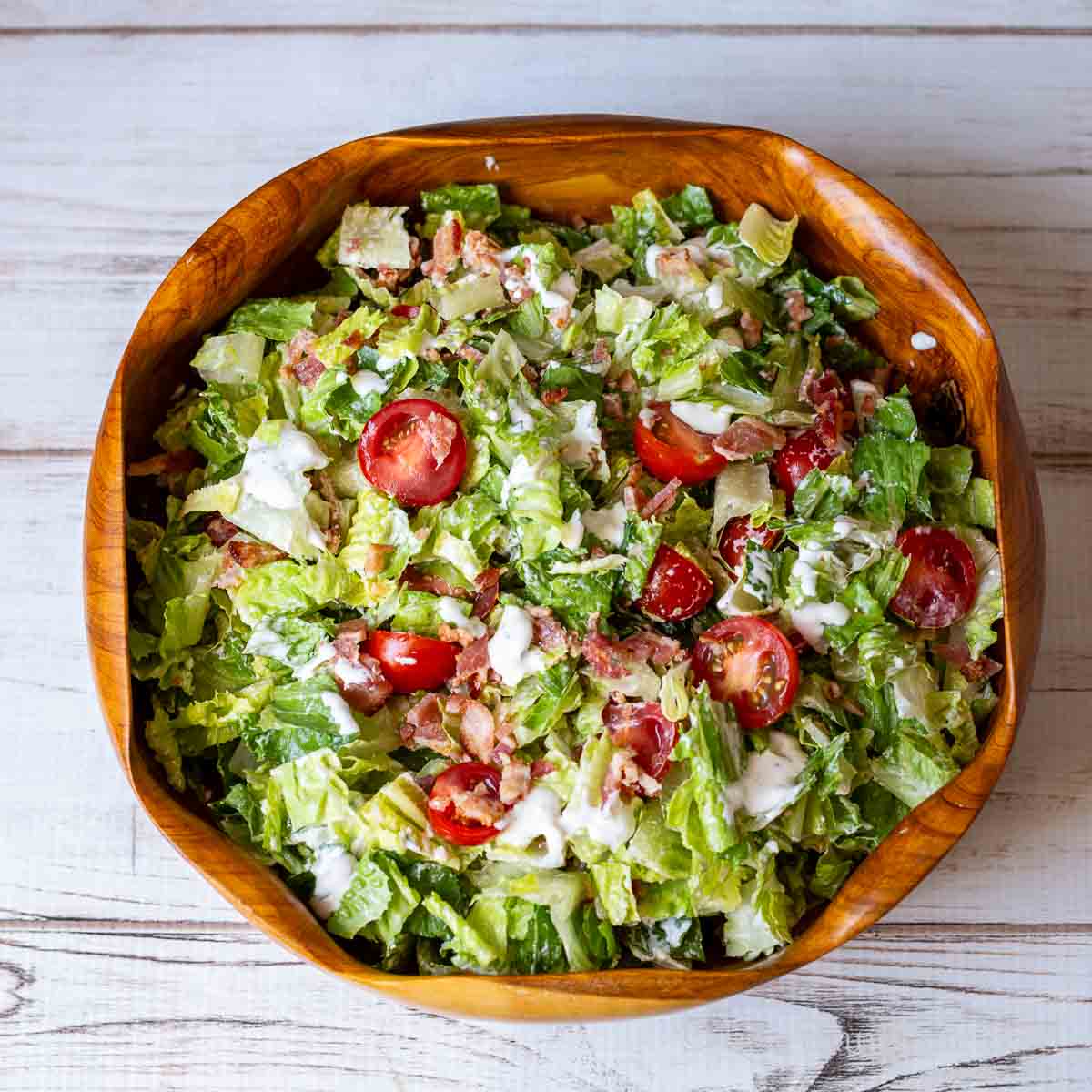 BLT salad with creamy blue cheese dressing in a wooden bowl.