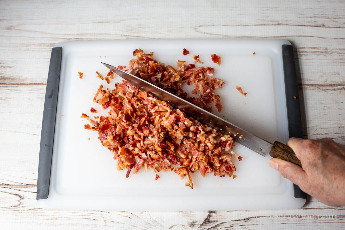 Cooked bacon chopped on a cutting board.