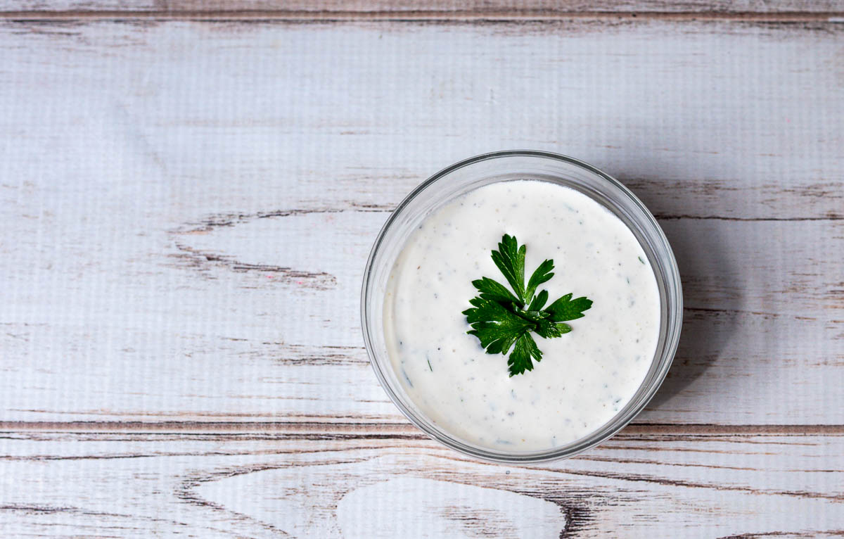 A small bowl of creamy blue cheese dressing with a parsley leaf in the middle.