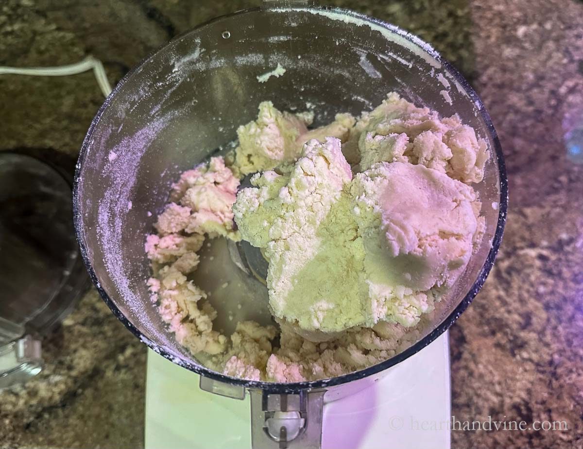 Water added to flour and butter mixture in the food processor bring the mixture into a dough ball.