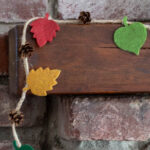 Small fall felt leaf and pinecone garland on the corner of a mantel.