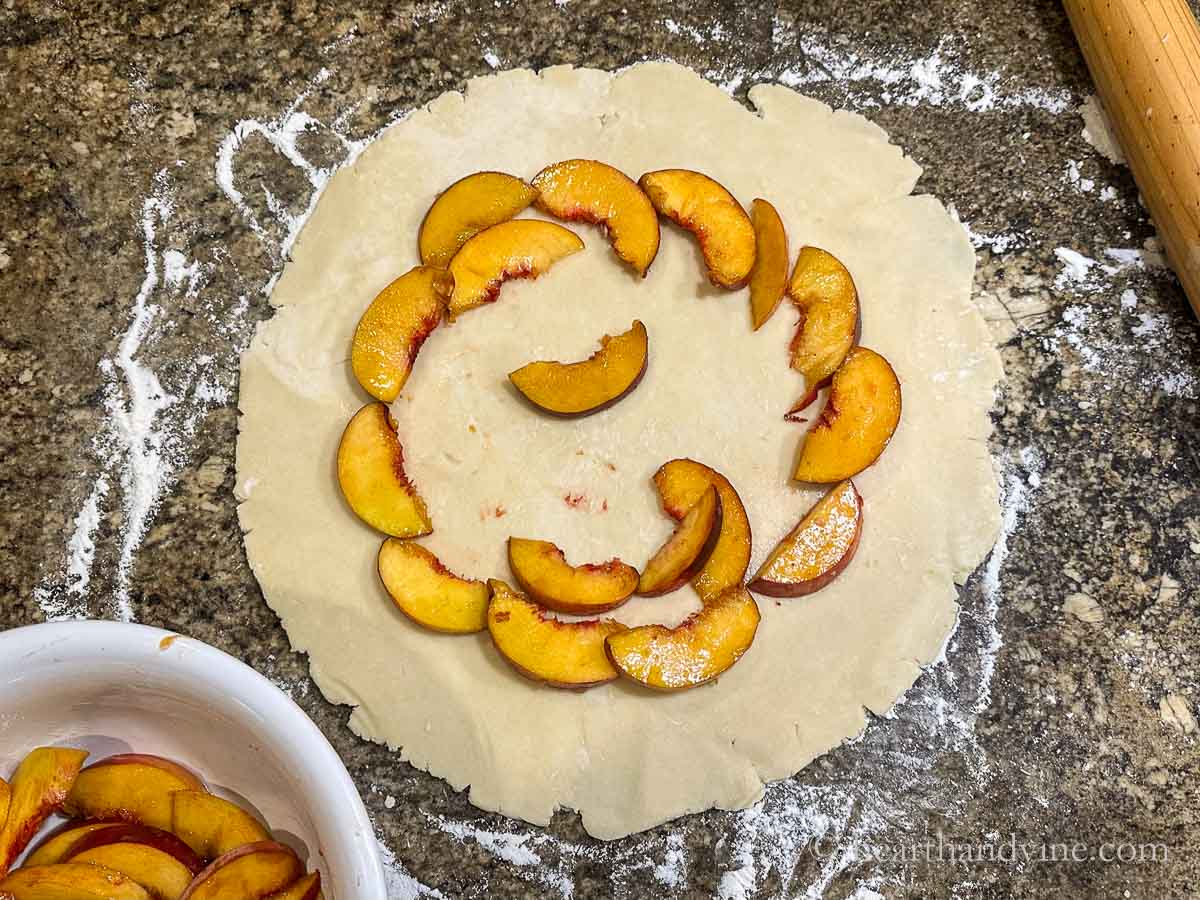 A circle of peach slices about 2 inches from the edge of the dough.