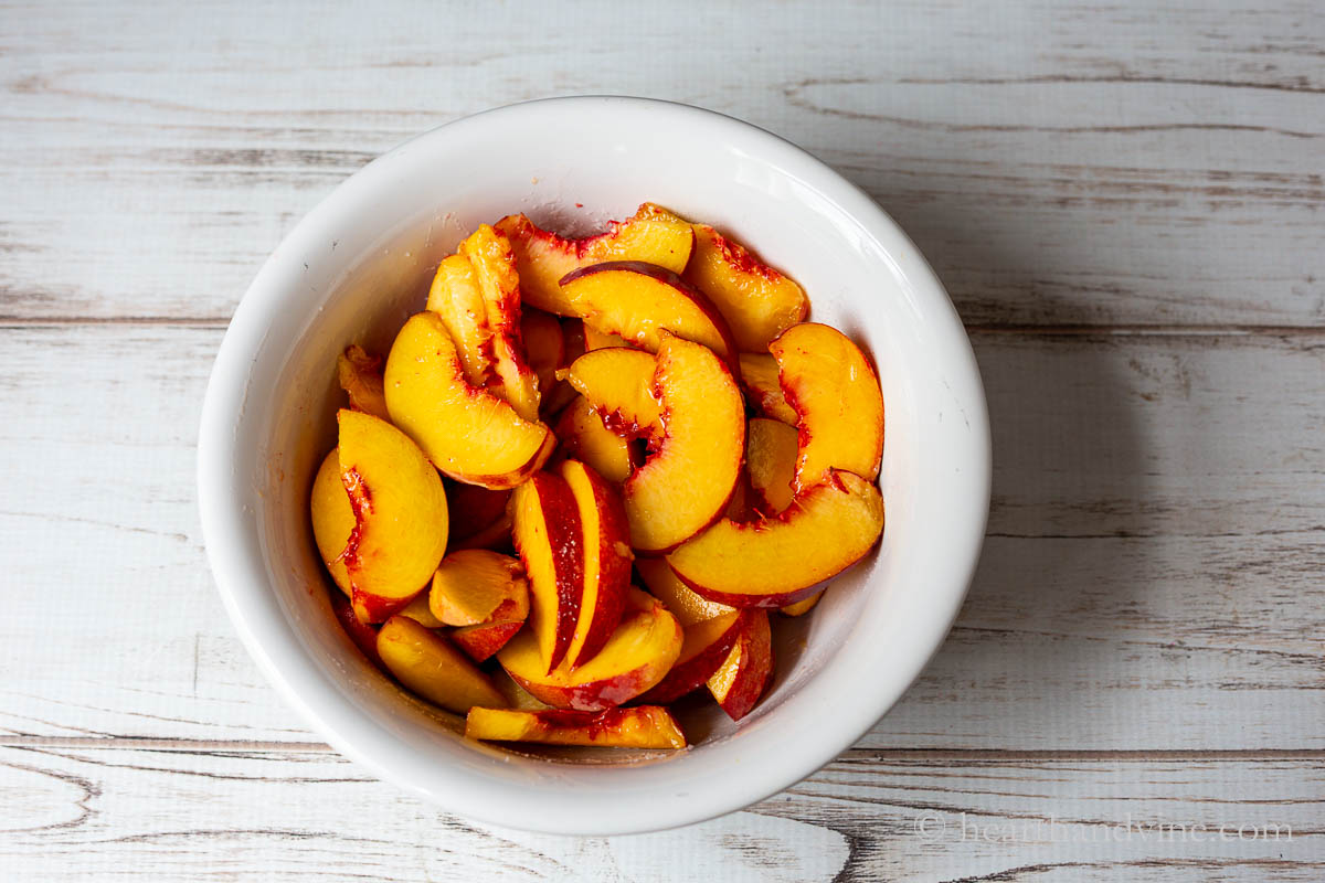 Slices of peaches in a large white bowl.