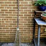 Homemade witch broom leaning on the brick of a house.