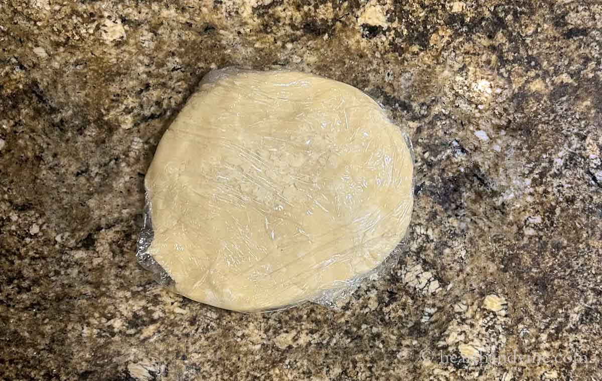 Dough worked into a round disc and wrapped in plastic.