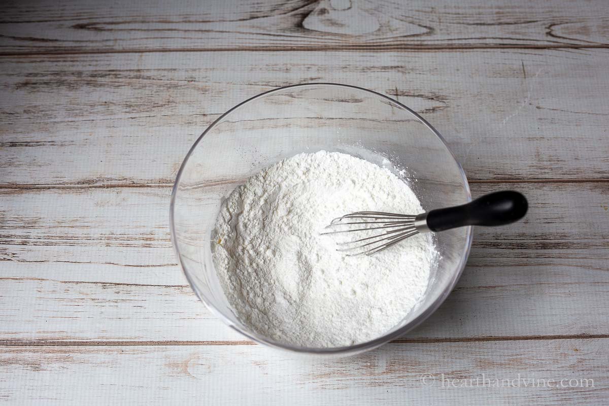 Dry bath bomb ingredients in a large bowl with a wire whisk.