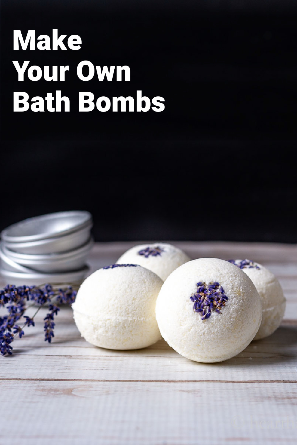 Lavender flower bath bombs next to metal molds and dried lavender flowers.