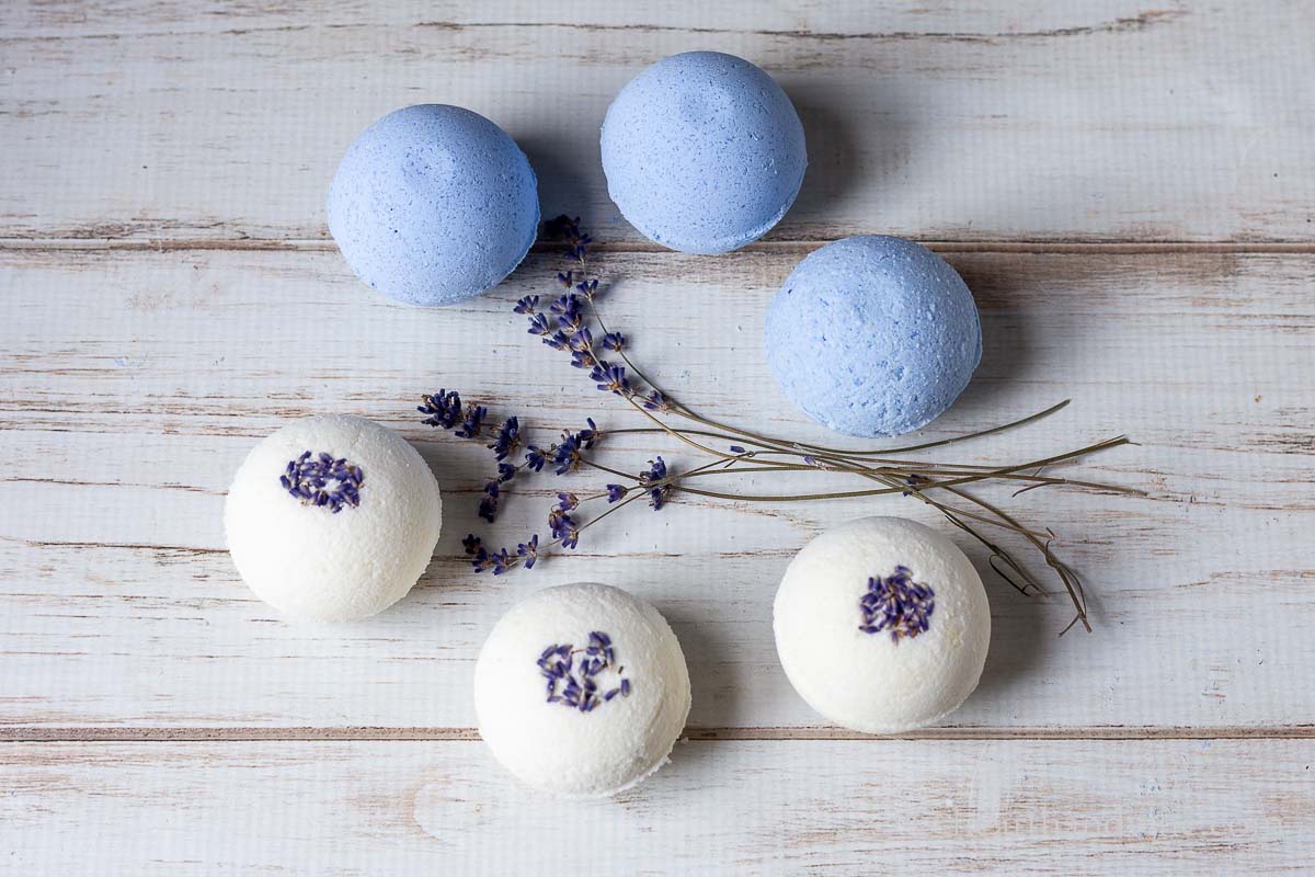 Three blue bath bombs and three lavender bud bath bombs with dried lavender flowers in the middle.