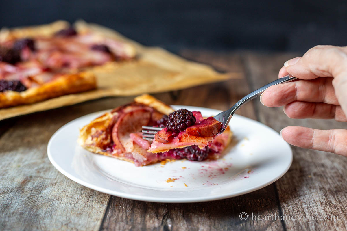 A forkful bite of a blackberry and pear tart.