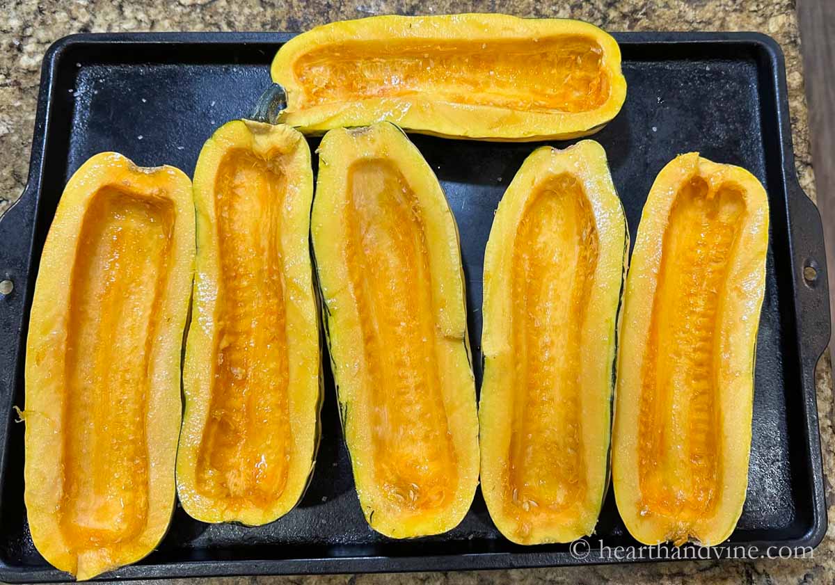Three delicata squash cut in half lengthwise, seeds removed and set on a baking sheet with a little olive oil and salt.