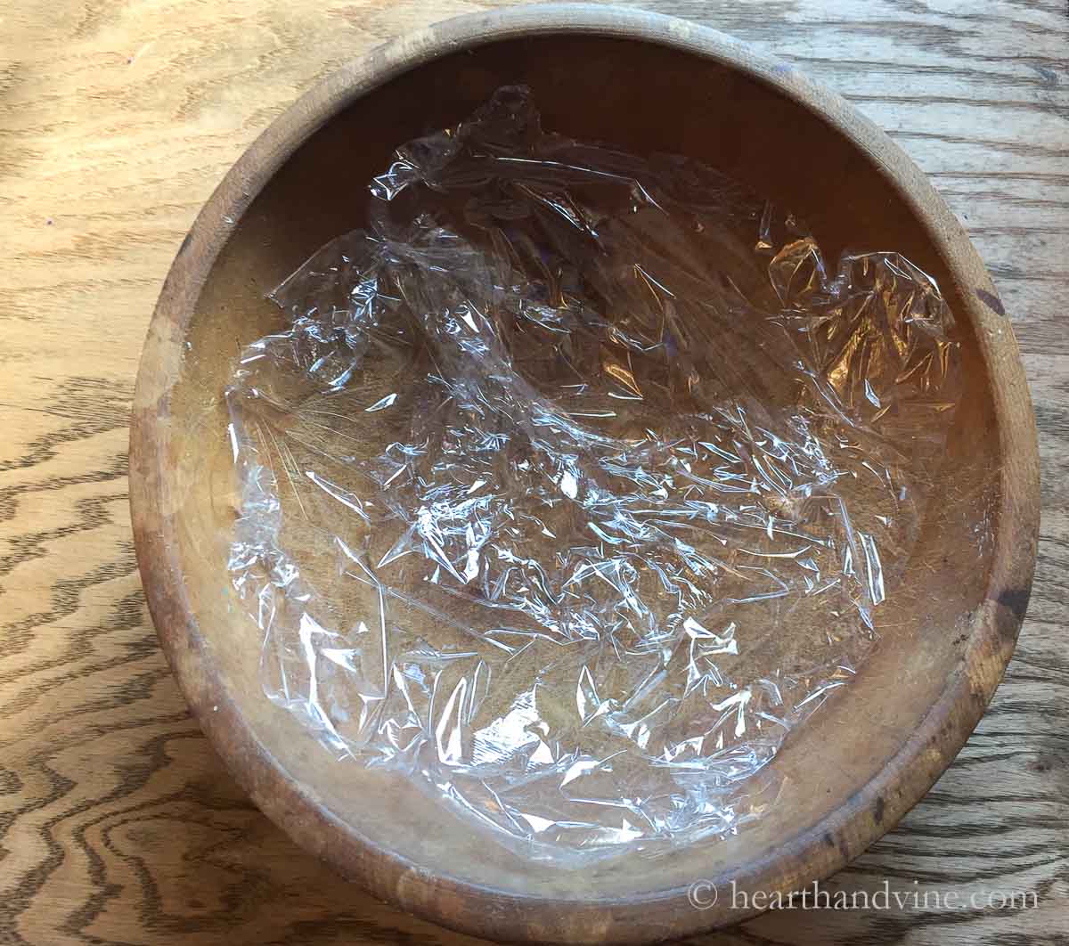 Large dough bowl with plastic wrap inside.