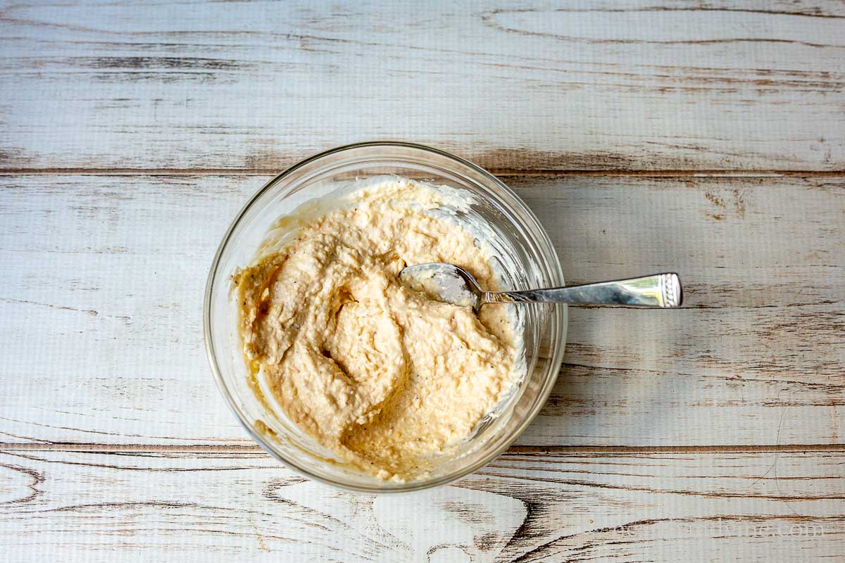 Bowl with Parmesan bites spread mix and a spoon.