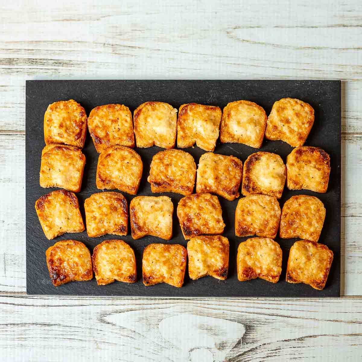 Parmesan bread bites on a slate serving tray.