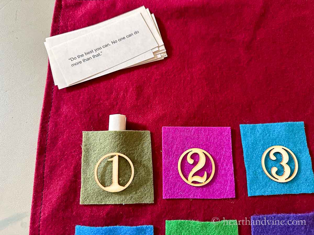 The top portion of an advent calendar with paper quotes rolled and stuffed into felt pockets.