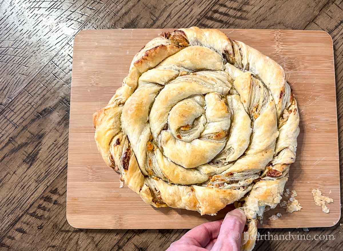A hand pulling off a bit the puff pastry spiral.