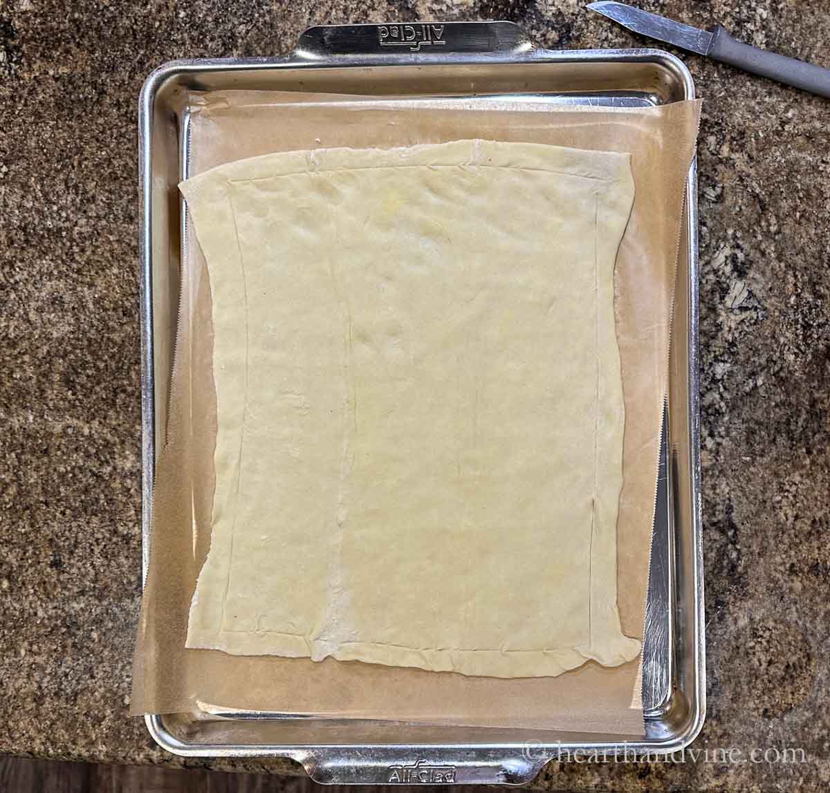 Puff pastry on parchment paper with edges scored.