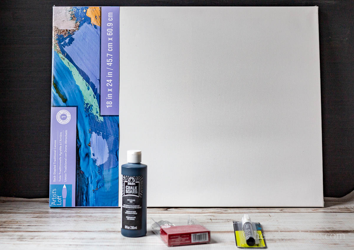 Supplies including a painter's canvas, black chalkboard paint, a white chalk paint marker and a set of mini LED lights with a battery pack.