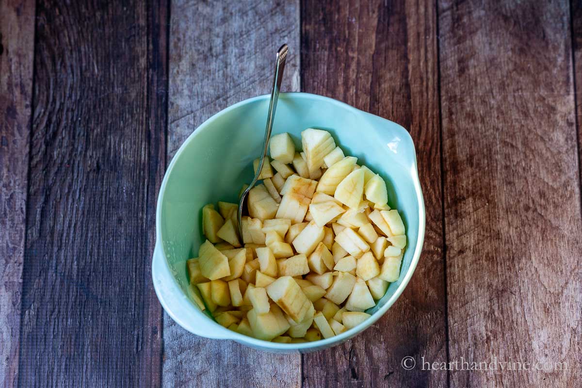 Chopped peeled apples with a little lemon juice in a bowl.