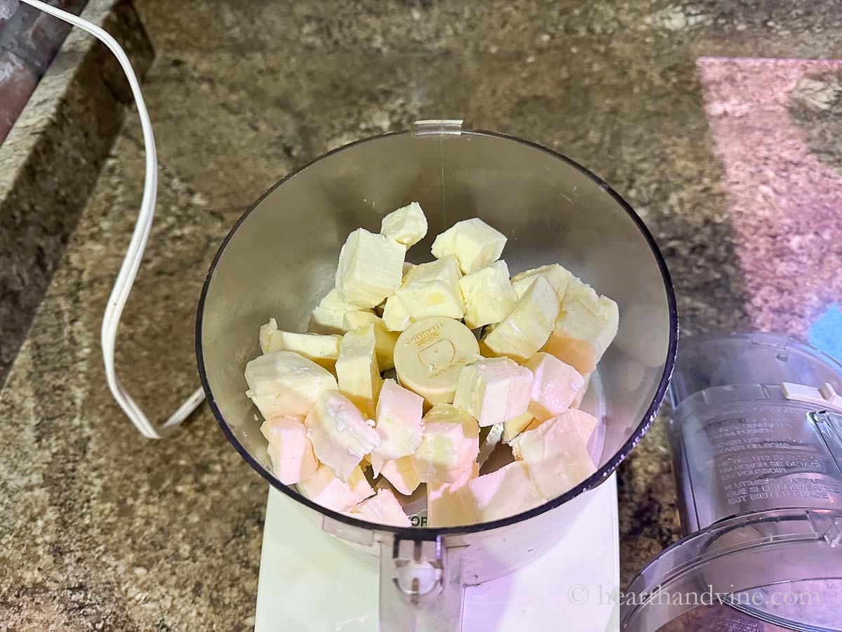 Cubes of brie cheese in a food processor getting ready to pulse.