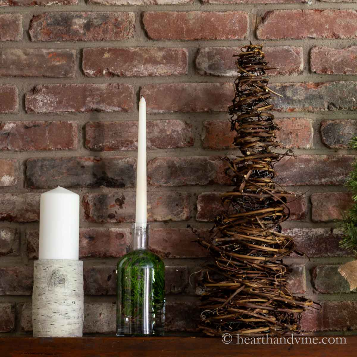 Cone shaped grapevine tree on a mantel with candles.