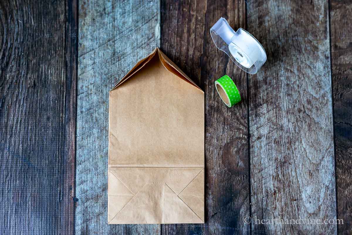 A brown paper bag with the top corners folded towards the middle, clear tape and washi green tape.