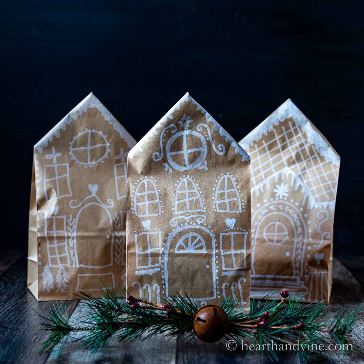 Three brown paper bags with gingerbread house drawn on the fronts.