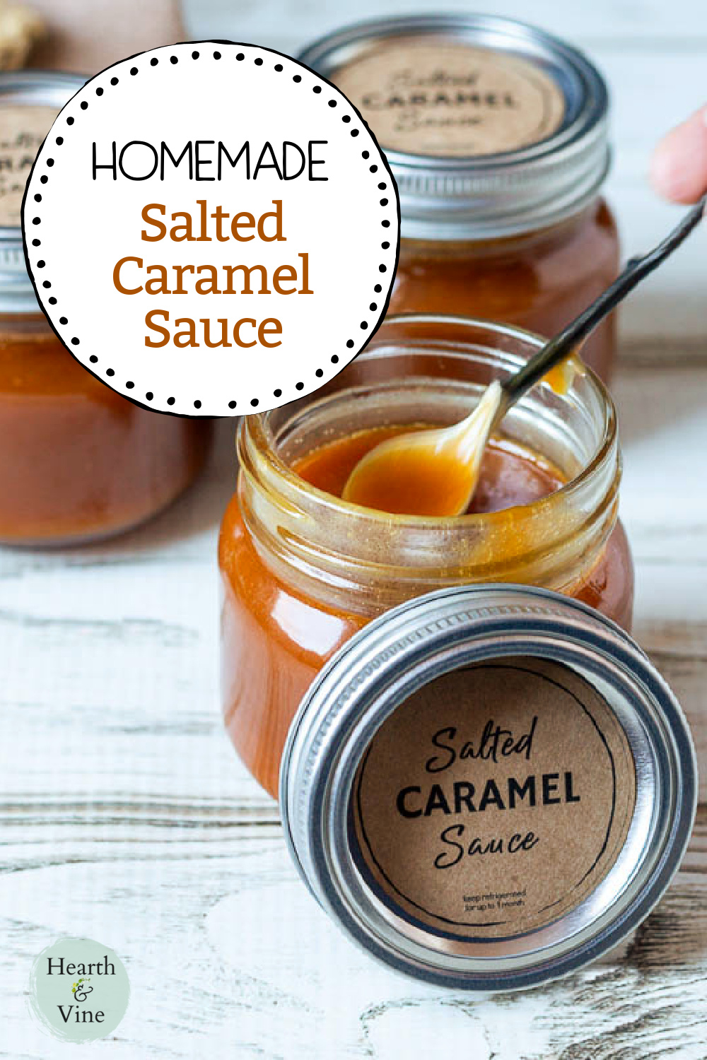An open jar of salted caramel sauce with the lid on the side showing the label and a small spoon in the jar.