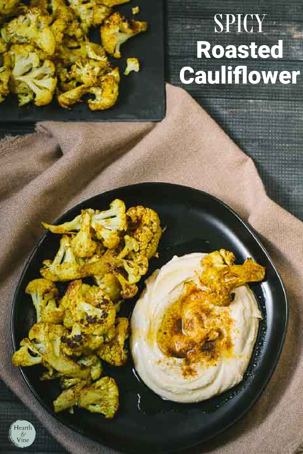 A plate of roasted cauliflower next to some hummus with spicy seasonings on both.