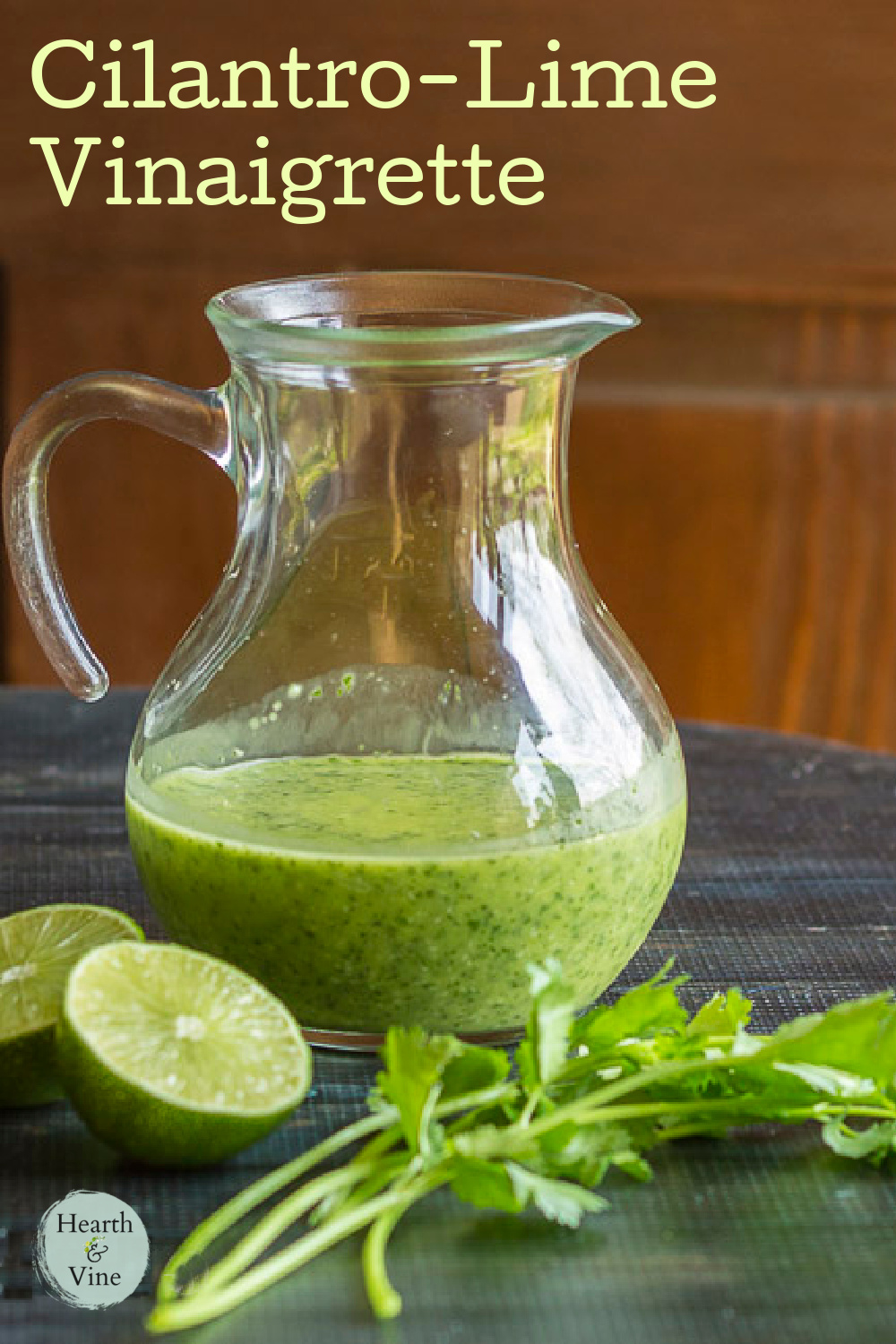 Sprigs of cilantro, a lime cut in half and a pitcher of cilantro lime vinaigrette.