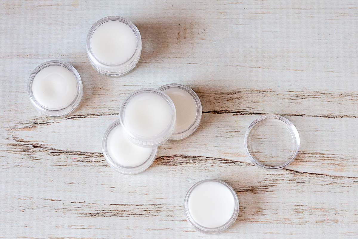 Six cuticle cream containers. One is open and the others are to the side.