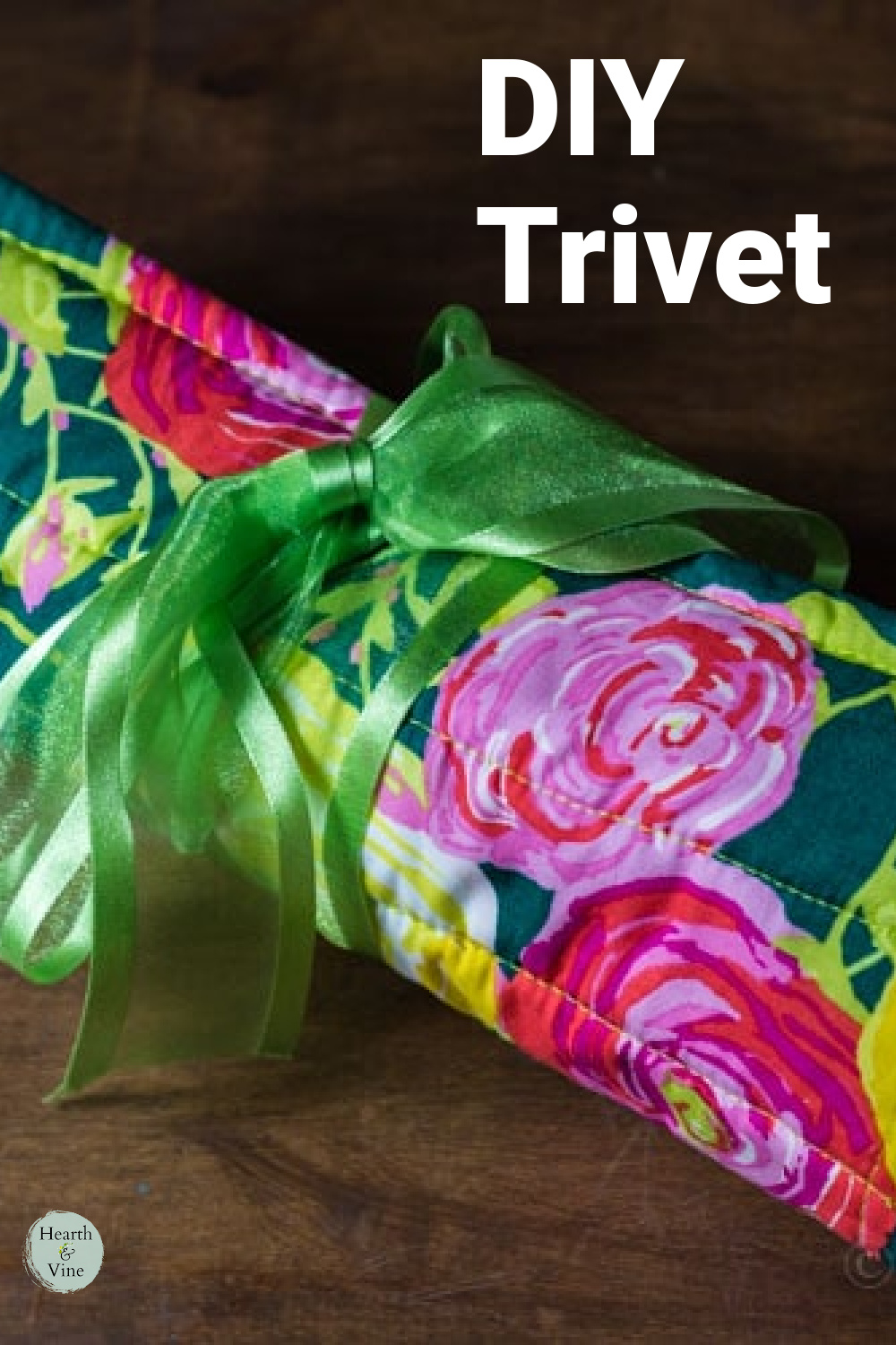 A floral patterned fabric turned into a quilted trivet rolled around wooden spoons and tied with a green ribbon.