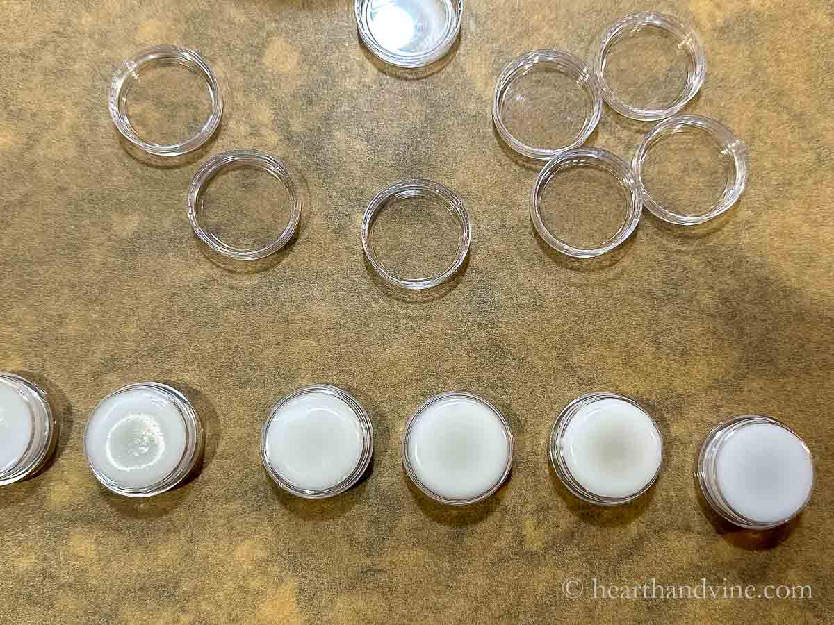 Small clear round plastic containers with cuticle cream pour into them and the cap above.