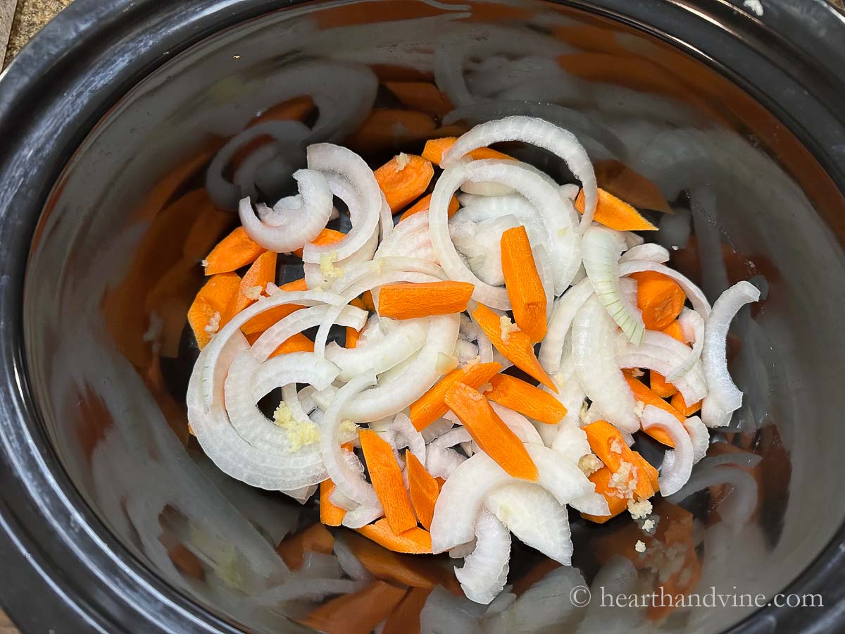 Slow cooker with onions, carrots and grated garlic.