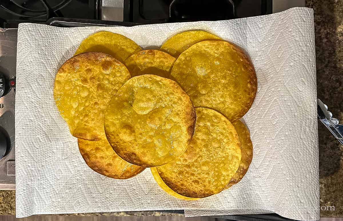 A group of fried corn tortillas on paper towels.