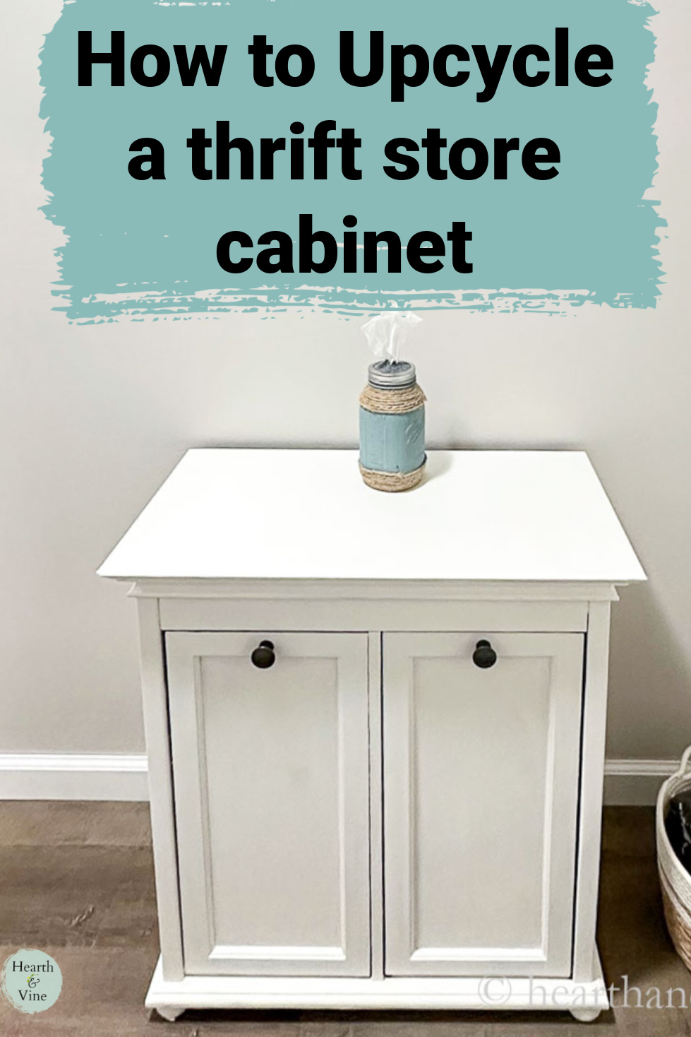 White floor cabinet with dark pulls and a mason jar tissue holder on top.