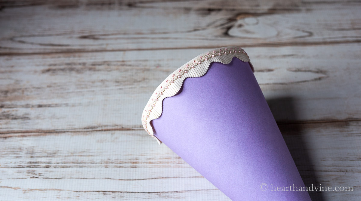 A pink scalloped ribbon trim is hot glued to the top edge of the flower cone.