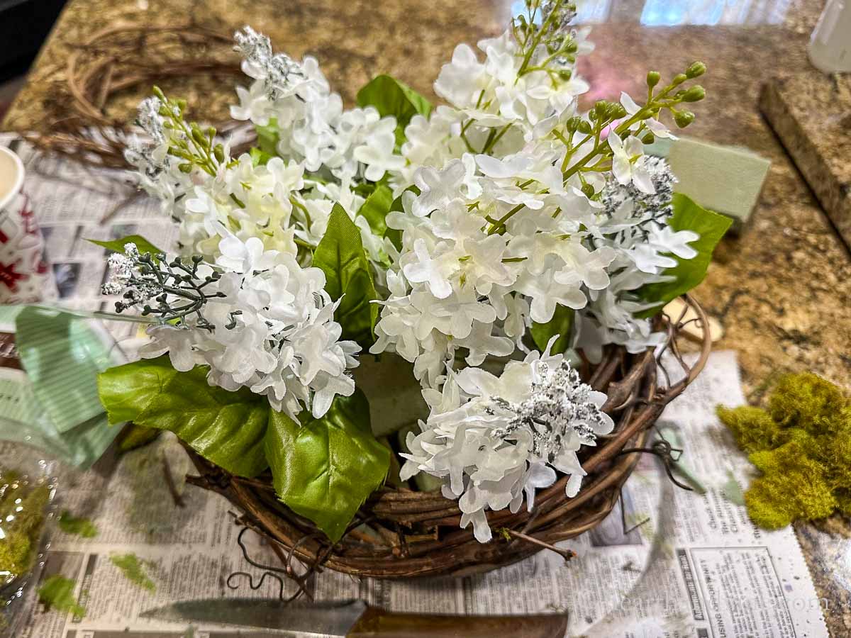 White artificial lilacs set into the floral foam.